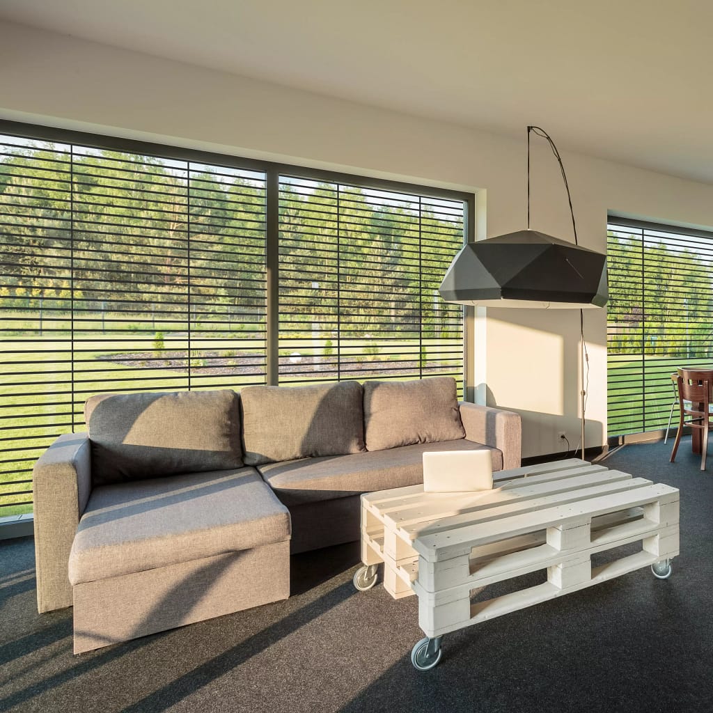 Vue intérieur d'un salon avec un canapé gris et une table en palette devant un brise soleil orientable rénovation gris de la marque Flip
