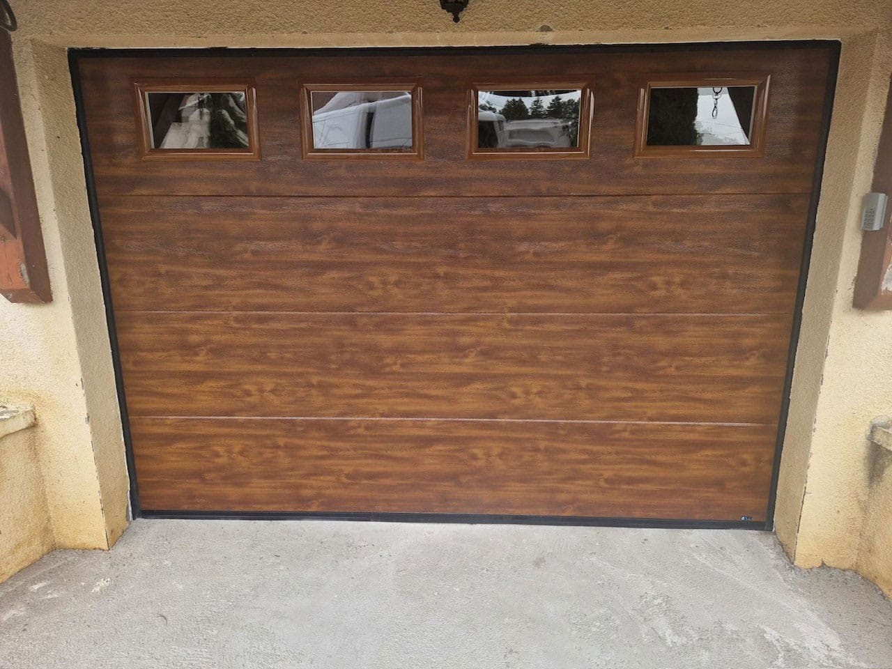 porte de garage sectionnelle coloris chêne doré équipée de hublots carrés fabriquée chez FLIP et installée à Valentigney dans le doubs