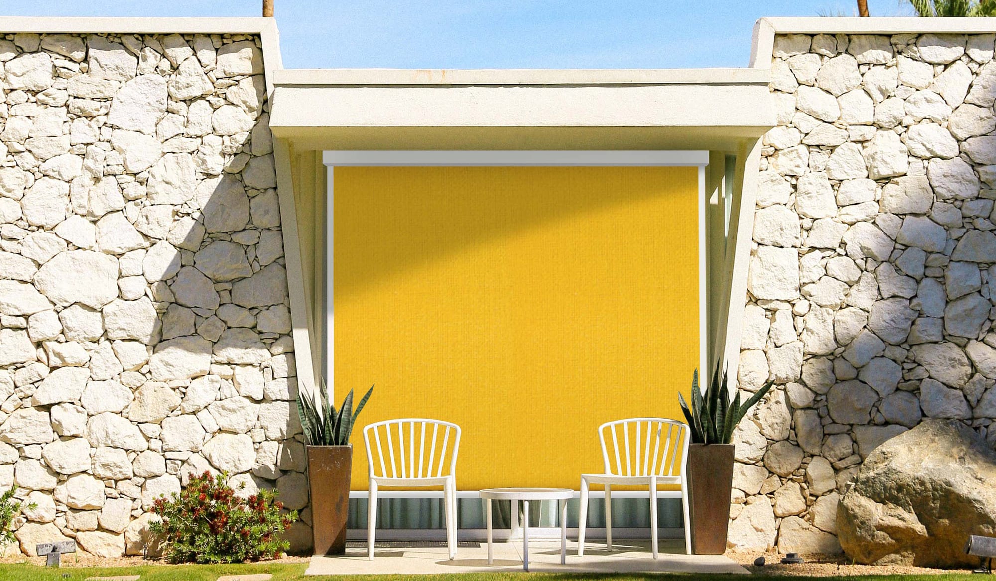 Vue extérieur d'une baie vitrée avec une store zip jaune de la marque flip, mur en pierre et palmiers