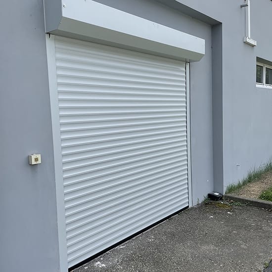 Porte de garage enroulable Dooralux blanc sur une façade d'une maison grise