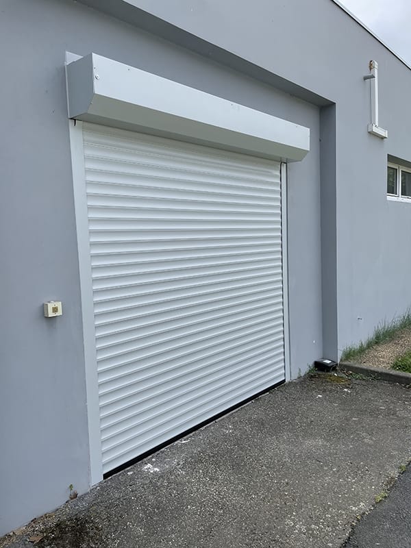 Porte de garage enroulable Dooralux blanc sur une façade d'une maison grise