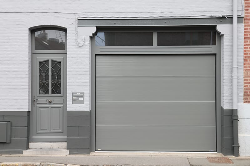 Maison de rue vue de l'extérieur avec porte de garage sectionnelle plafond grise clair et microrainures