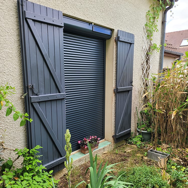 Porte fenêtre d'une maison à la façade crépis beige équipée d'un volet roulant astrosun renosun noir de la marque Flip