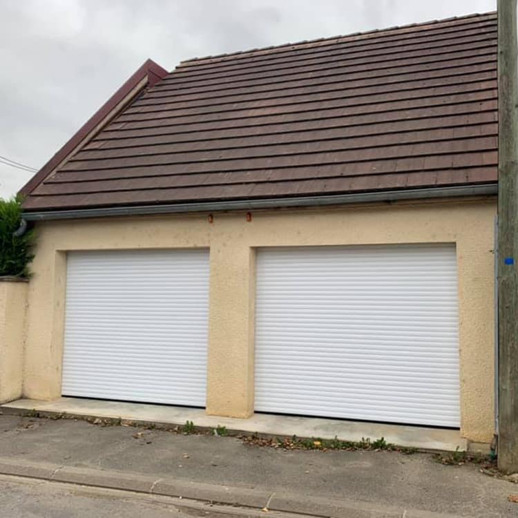 Double porte de garage enroulable Dooralux blanches sur une façade en crépis beige