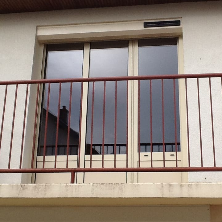 Vue d'un balcon avec un volet roulant astrosun renosun beige de la marque Flip et rambarde bordeaux