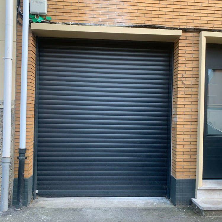 Porte de garage enroulable Dooralux noire isolée devant une maison en brique marrons