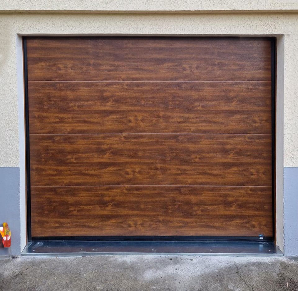 porte de garage sectionnelle coloris chêne doré équipée de hublots carrés fabriquée chez FLIP et installée à Valentigney dans le doubs
